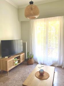 ein Wohnzimmer mit einem Flachbild-TV und einem Tisch in der Unterkunft Athens Modern Living in Athen
