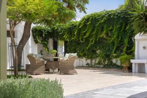 patio z wiklinowymi krzesłami, stołem i drzewami w obiekcie Kouneni Apartments w mieście Mykonos