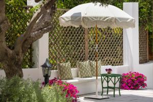 a white bench with an umbrella and a table at Kouneni Apartments in Mikonos