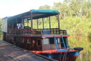 Orangutan Kelotok Houseboat for 6 person في بانكالان بون: يتم رسو قارب بجوار رصيف الميناء