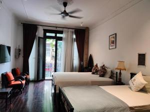 ein Hotelzimmer mit 2 Betten und einem Deckenventilator in der Unterkunft Centraltique Downtown - Bespoke Colonial House Near Hoan Kiem Lake in Hanoi