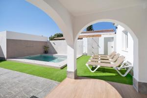 ein weißes Haus mit einem Pool und einer Chaiselongue in der Unterkunft Rchico Piscina climatizada 1diciemb in Chiclana de la Frontera