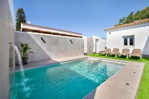 チクラナ・デ・ラ・フロンテーラにあるRchico Piscina climatizadaの滝のある家の裏庭にあるプール