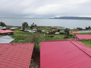 vistas a una ciudad con techos rojos y un cuerpo de agua en TITIKAKA NATURAL LODGE - LUQUINA en Chucuito
