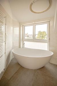 a white bath tub in a bathroom with a window at DASWEINBERG contactless check-in in Podersdorf am See