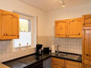 eine Küche mit Holzschränken, einem Waschbecken und einem Fenster in der Unterkunft Ferienwohnung Am Berg, Eheleute Müller in Hilchenbach