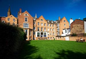 un gran edificio de ladrillo con un césped verde delante de él en St Chad's College en Durham