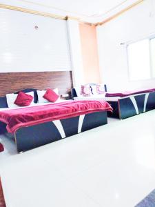 2 camas en una habitación con almohadas rojas en New Ashi Palace, en Varanasi