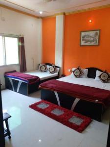 2 camas en una habitación con paredes de color naranja en New Ashi Palace, en Varanasi