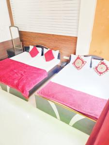 2 camas con almohadas rojas en una habitación en New Ashi Palace, en Varanasi