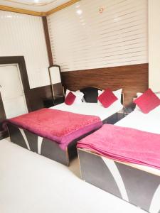 Pokój z 3 łóżkami i czerwonymi poduszkami w obiekcie New Ashi Palace w mieście Waranasi