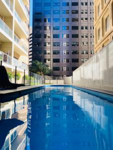 uma piscina em frente a um edifício alto em 2 Bedroom Apartment @ Grenfell Street em Adelaide