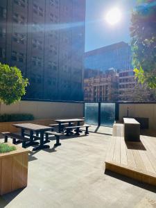 um pátio com mesas de piquenique e um grande edifício em 2 Bedroom Apartment @ Grenfell Street em Adelaide