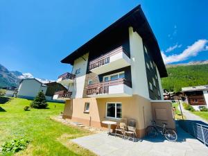 een groot huis met een balkon op een heuvel bij Appartment Alpenrose in Saas-Fee