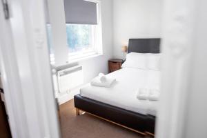 a bedroom with a white bed and a window at Glovers Lodge - Charming 3 Bed Retreat near City Centre in Derby