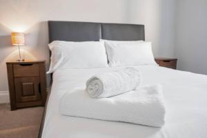 uma cama branca com toalhas com mesa de cabeceira em Glovers Lodge - Charming 3 Bed Retreat near City Centre em Derby