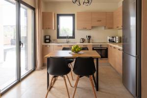 een keuken met een houten tafel en zwarte stoelen bij Dioni Pool House in Ialyssos