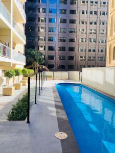 uma piscina em frente a um edifício alto em 2 Bedroom Apartment @ Grenfell Street em Adelaide