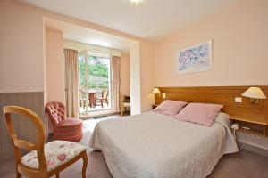 a bedroom with a bed and a chair and a window at Le Terminus des P&egrave;lerins in Rocamadour