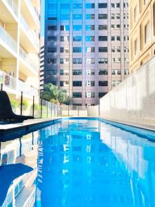 a swimming pool in front of a tall building at Bundled Bliss 2 bedroom Condo in Adelaide CBD in Adelaide