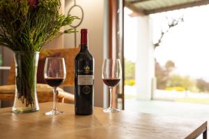 una botella de vino sentada en una mesa con dos copas en Saxenburg Wine Farm en Kuilsrivier