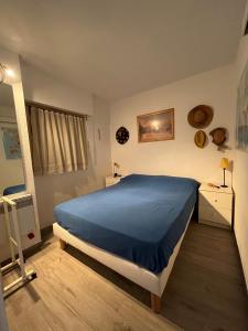 1 dormitorio con 1 cama con colcha azul en Appartement avec vue mer et piscine, en Théoule-sur-Mer