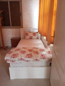 a small bedroom with a bed with a flowered blanket at amal's apart&studio in Agadir