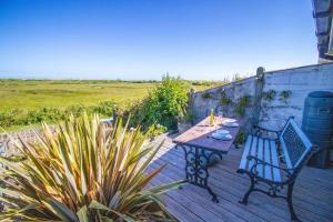 a wooden deck with a table and a bench at Ebb n Flow - 2 Bed - Nature Reserve & Beach Views in Winchelsea