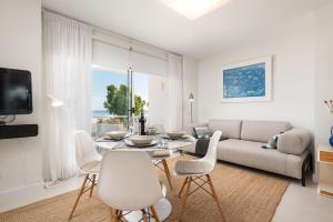 a white living room with a table and a couch at Apartment Blue View in Port d'Alcudia