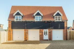 a house with four garage doors in front of it at The Coach House W in Wells next the Sea