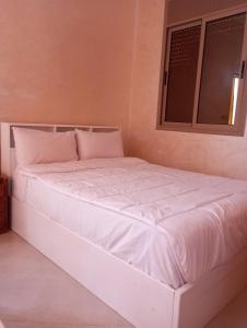 Cama blanca en habitación con ventana en amal's apart&studio, en Agadir