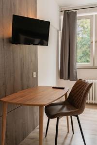 a wooden table with a chair and a television on a wall at Hotel Enger Hof in Düsseldorf