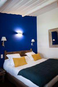 Un dormitorio con una pared azul y una cama con almohadas amarillas. en Oustau Camarguen Hôtel & Spa, en Le Grau-du-Roi