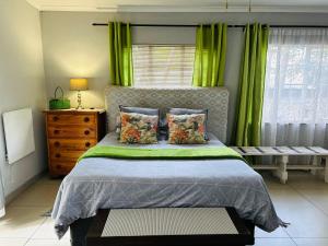 a bedroom with a bed with green curtains and a window at Sabie Self Catering Apartments in Sabie