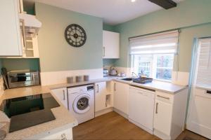 a kitchen with a washing machine and a clock on the wall at Flint Cottage - 2 Bedrooms - Rye Town Centre in Rye