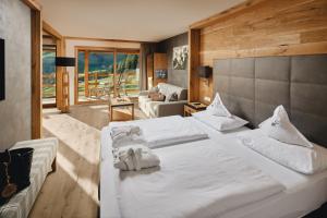 a bedroom with a large white bed and a living room at Cyprianerhof Dolomit Resort in Tires