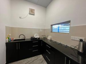 a kitchen with black cabinets and a sink and a window at Aara Holiday Home in Trincomalee