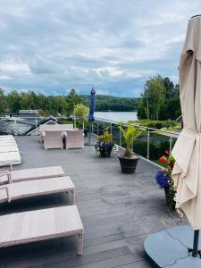 a deck with chairs and tables and a view of the water at Luxory Vättern Lake Villa in Motala
