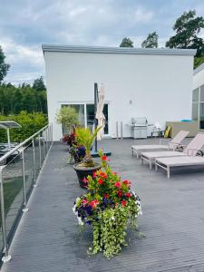 a wooden deck with flowers and benches on a building at Luxory Vättern Lake Villa in Motala