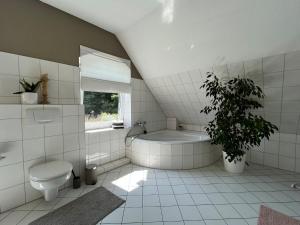 ein Badezimmer mit einer Badewanne, einem WC und einer Pflanze in der Unterkunft Hof Langenberg in Schwanewede