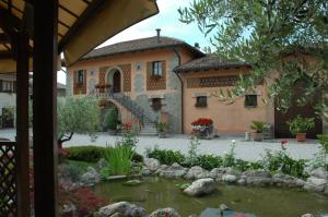 una casa grande con un estanque frente a ella en AZIENDA AGRICOLA MOSCHIONI, en Cividale del Friuli