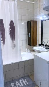 a bathroom with a tub and a sink with a feather shower curtain at RynekArt Apartment in Świdnica