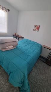 a bed with a blue comforter in a room at Casa de 3 ambientes in Río Grande