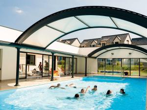 - un groupe de personnes se baignant dans une piscine dans l'établissement Comfortable holiday home close to a golf course in Brittany, à Quéven