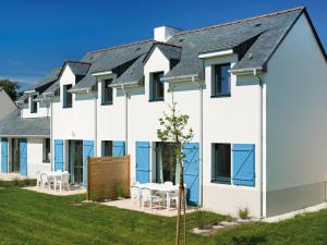 une maison blanche avec des fenêtres bleues, une table et des chaises dans l'établissement Comfortable holiday home close to a golf course in Brittany, à Quéven