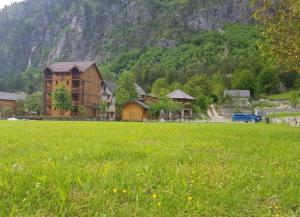 un gran campo verde con una casa y una montaña en Residence: Quku i Valbones, en Valbonë