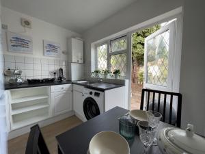 a kitchen with white cabinets and a table with chairs at Pass the Keys Cosy Studio Flat Close To Bexleyheath Centre in Bexleyheath