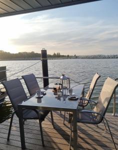 a table and chairs on a boat on the water at Hausboot Fjord Baltica mit Dachterrasse in Barth in Barth