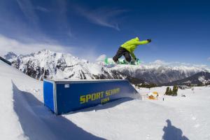 a snowboarder jumping over a sign in the snow at Haus Müller in Fiss