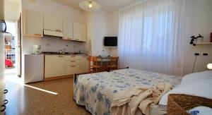 a small bedroom with a bed and a kitchen at Appartamenti Gaby in Lignano Sabbiadoro